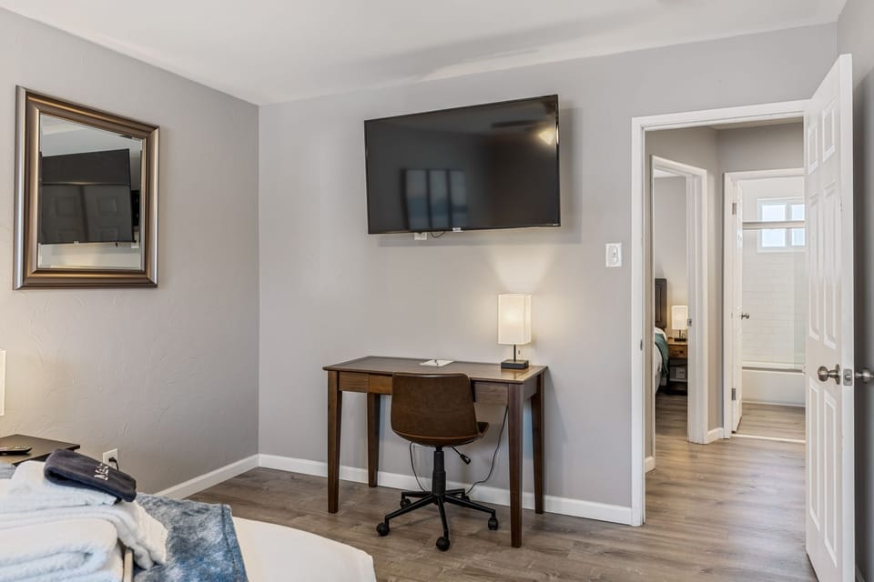 Opposite bedroom angle with a wall-mounted television and compact desk workspace.