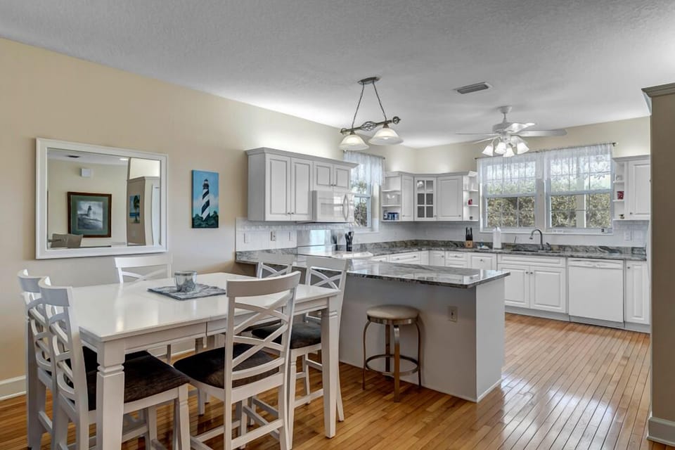 - Gather for meals in this bright dining area with seating for six and nearby bar stools for extra guests
- Open layout flows smoothly from kitchen to living, making group stays a breeze
- Soft lighting and coastal colors enhance the space