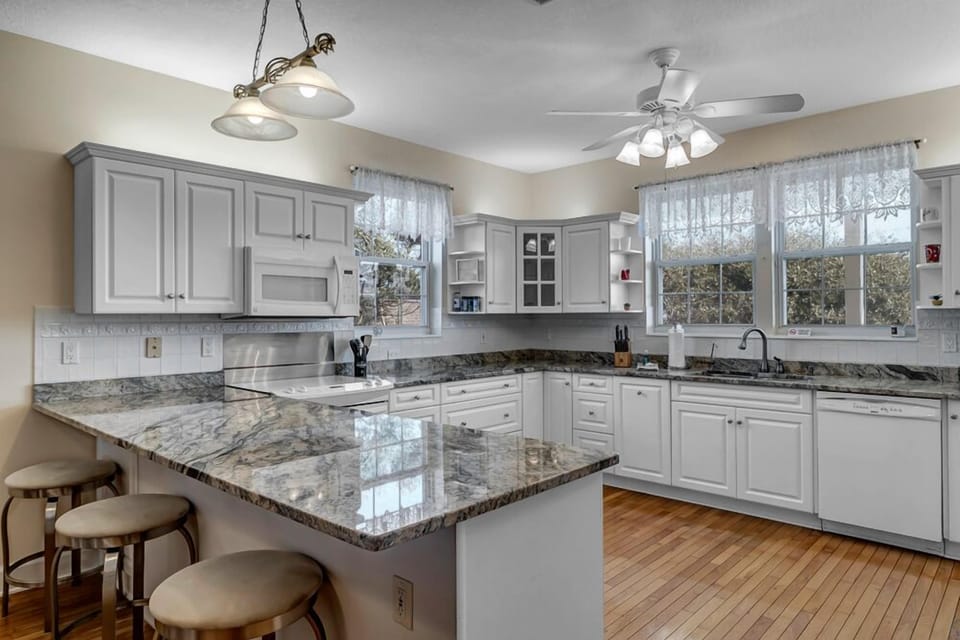 - Spacious L shaped kitchen boasts granite countertops, white cabinetry, and plenty of prep space
- Natural light pours in through large windows, perfect for morning cooking
- Fully equipped with appliances and bar seating along the edge