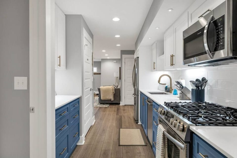 "Prepare your meals in style with our modern kitchen, boasting classic blue cabinets complemented by chic gold hardware. It's a space where functionality meets sophistication."
