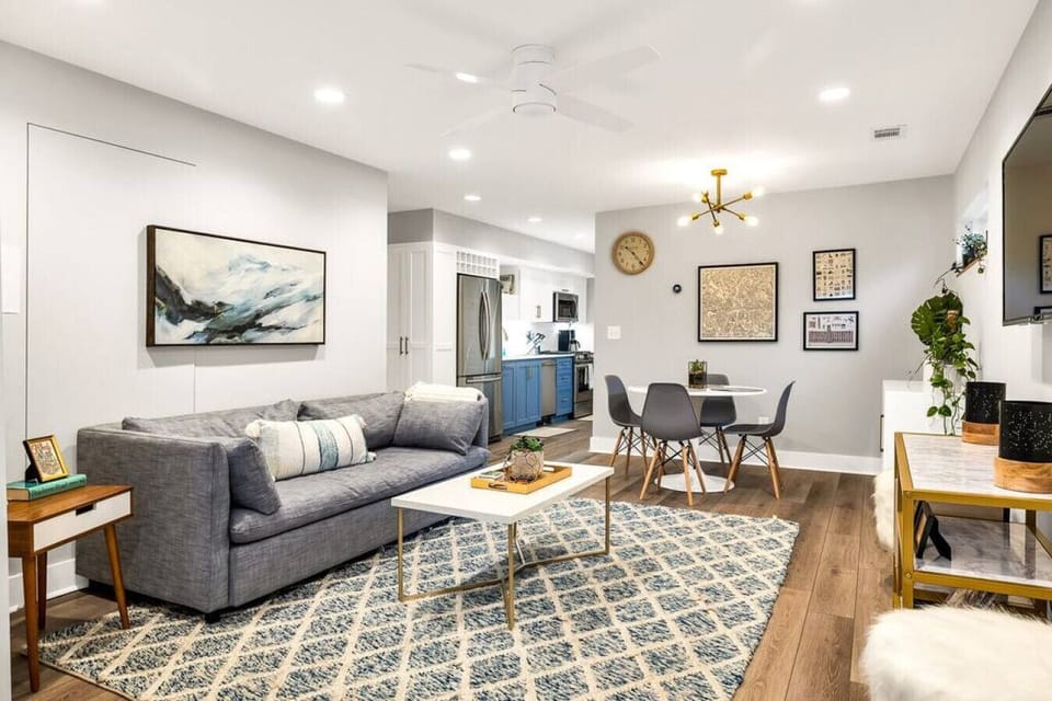 Discover the perfect blend of style and comfort in our inviting living area. Designed for relaxation and conversation, this space features a plush grey couch, a stylish gold-accented coffee table, and an elegant dining area, all anchored by a beautiful ab