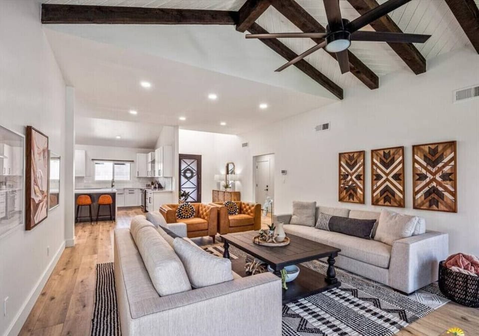 Sink into plush sectional seating beneath rustic exposed beams, where your open-concept retreat flows seamlessly into a bright modern kitchen.