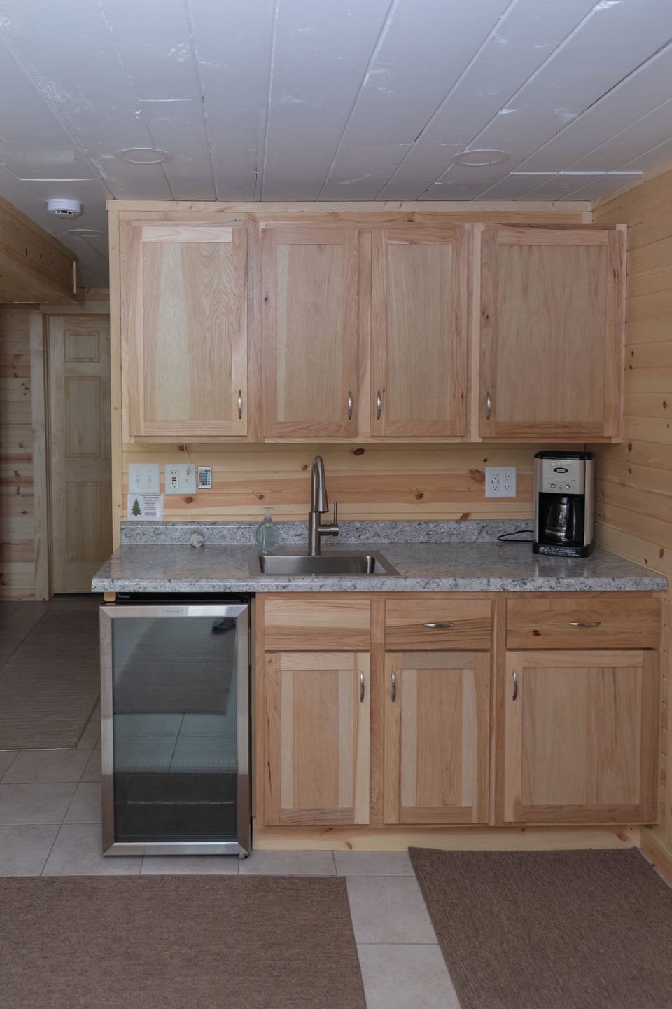 Coffee bar area with supplies, sink, beverage fridge & garbage/recycling