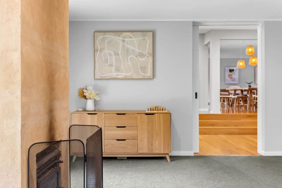 Living room accent wall with wooden cabinet and artistic touches.