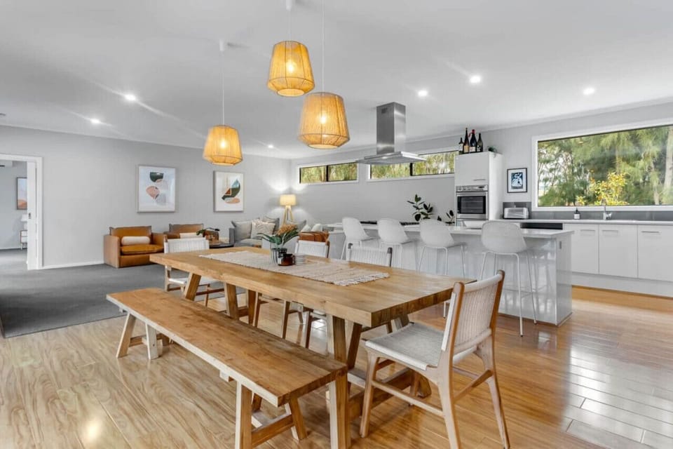 The long dining table stands as the centerpiece of the space, offering both functionality and charm. Surrounding it, wooden chairs add a touch of warmth with their natural tones and sturdy craftsmanship. Together, they create an inviting setting—perfect f