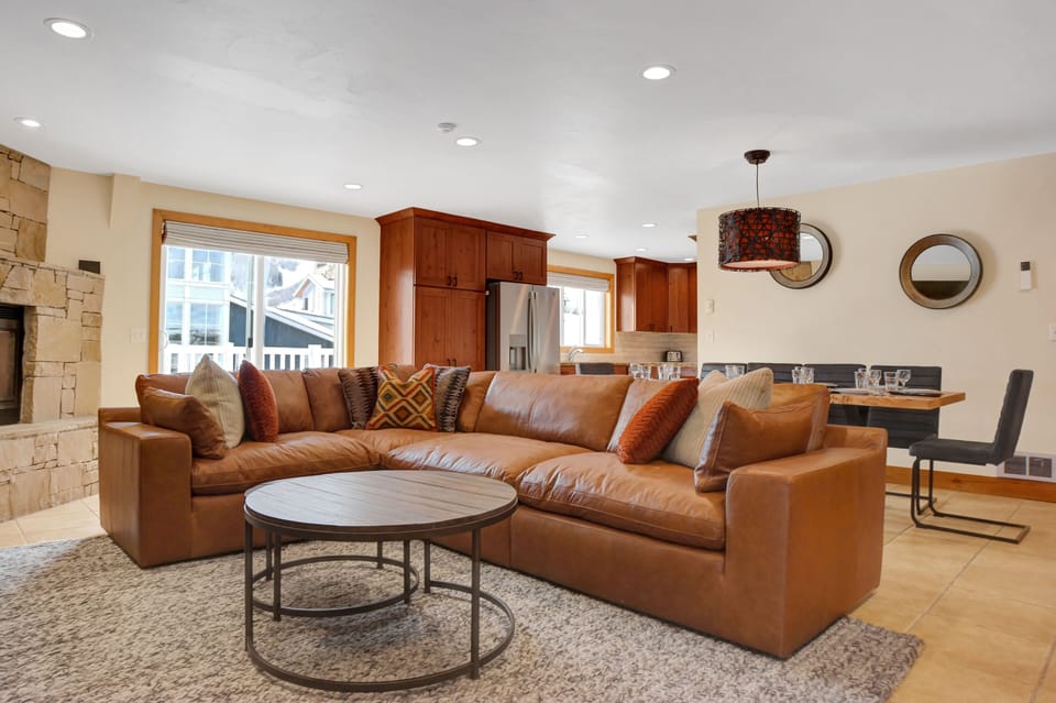 Brown leather sectional couch in the living room with circular modern wooden coffee table