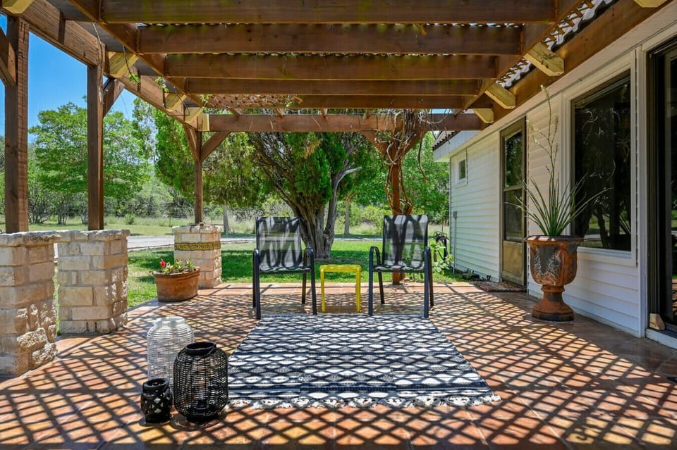 Shaded pergola patio with lounge chairs and lanterns—sip coffee or evening cocktails while watching wildlife around Road Runner Lodge.