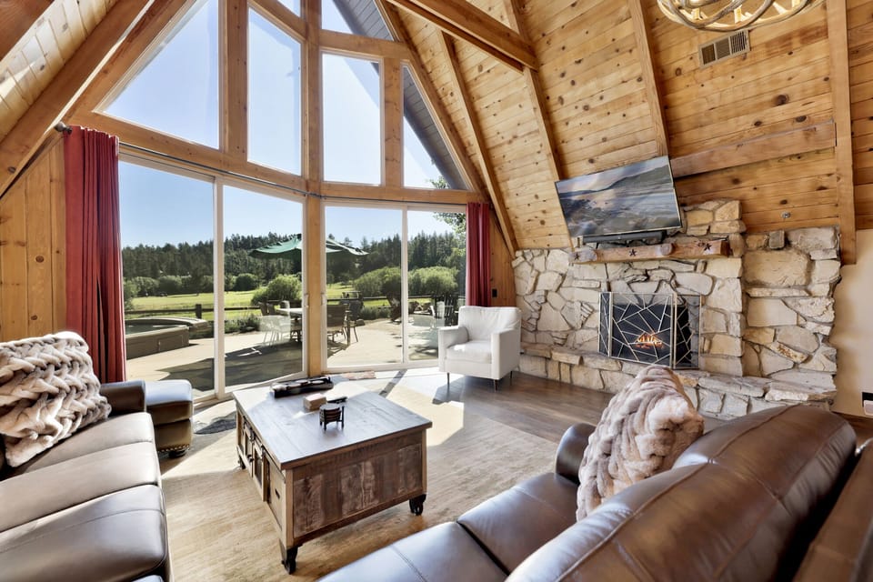 Cozy mountain living room with a stone fireplace, comfy seating, and smart TV—perfect for relaxing evenings, movie nights, and warm cabin vibes after outdoor adventures.