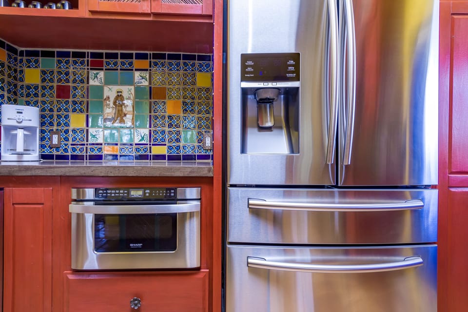 Coffee/tea bar next to refrigerator, with built-in microwave beneath. 