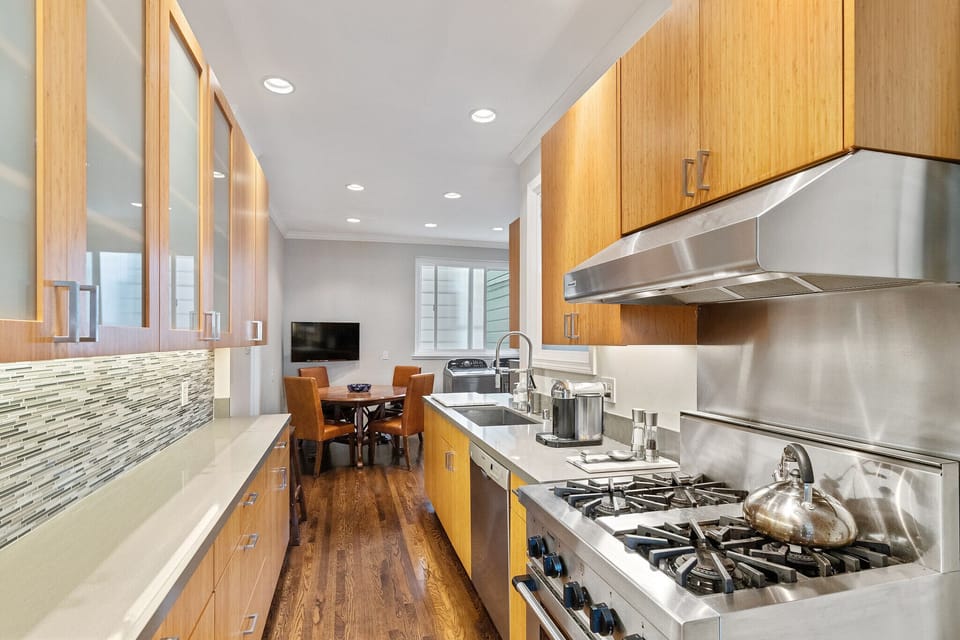 Kitchen features stainless steel appliances, quartz countertops & kitchen table.