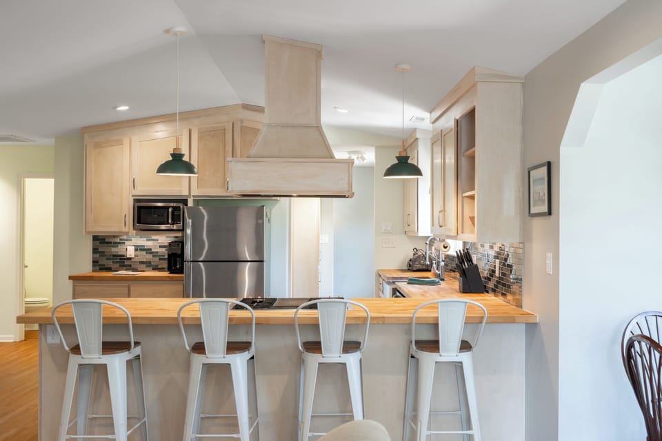 Open kitchen/living with butcher block, gas stove, peninsula seating & fireplace