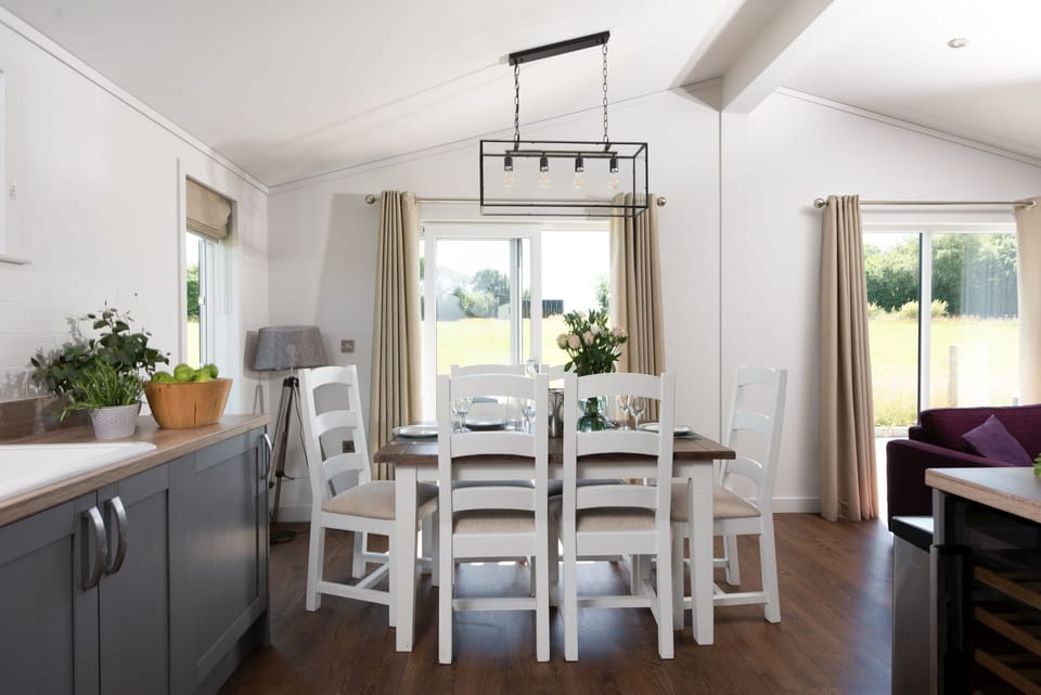 A dining table and chairs for all guests to eat together or play games - Forget Me Not Lodge