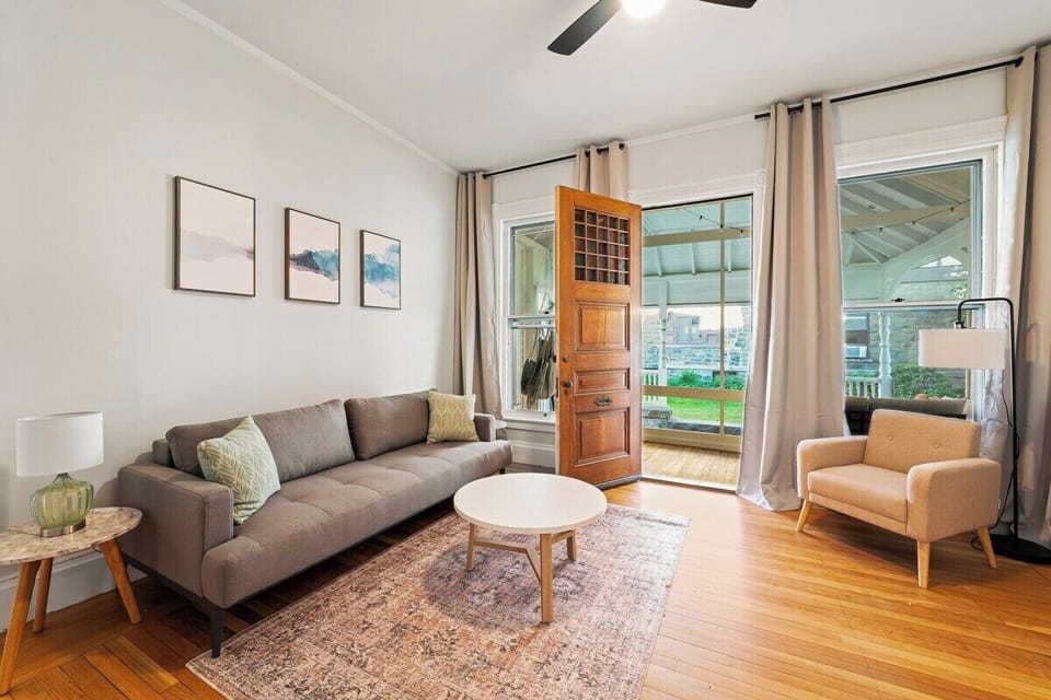 Living room with stunning historic stained glass doorway features, enclosed porch access, Roku TV, and Queen Sleeper Couch