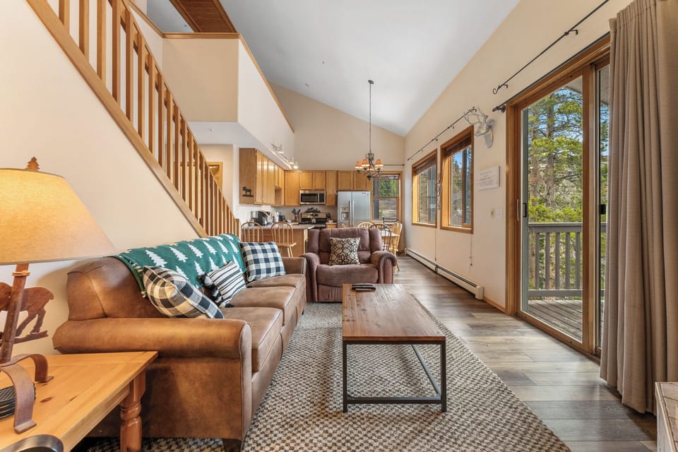 Living area featuring hardwood floors, vaulted ceiling, flat screen TV, gas fireplace and access to the private balcony.