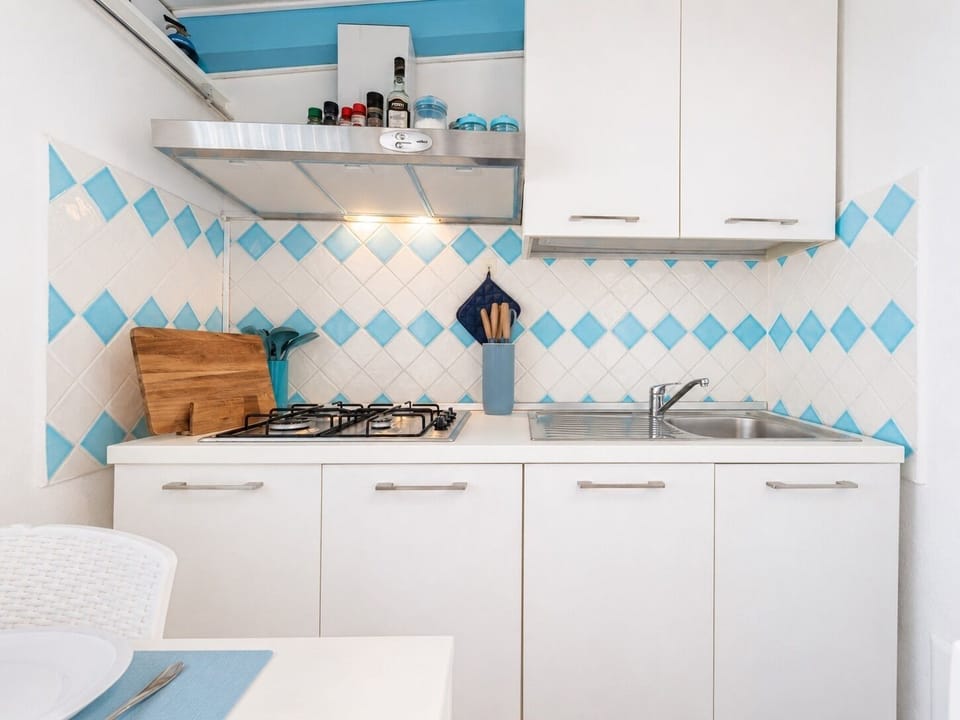 Bright coastal-style kitchen with gas cooktop and cheerful blue tiles