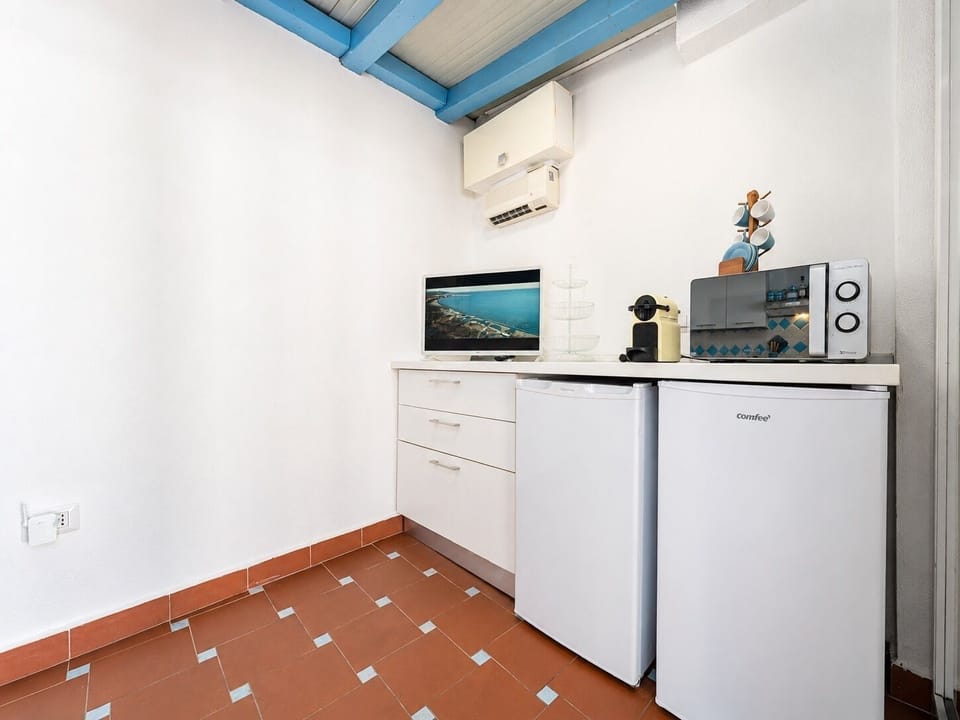 Bright kitchenette nook with mini fridge, microwave, TV, and AC