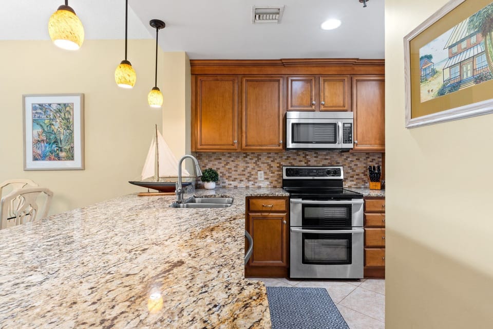 The kitchen is fully equipped with granite counters, double sinks, disposal, microwave, coffee pot, blender, toaster, can opener, and a double 
oven/range.