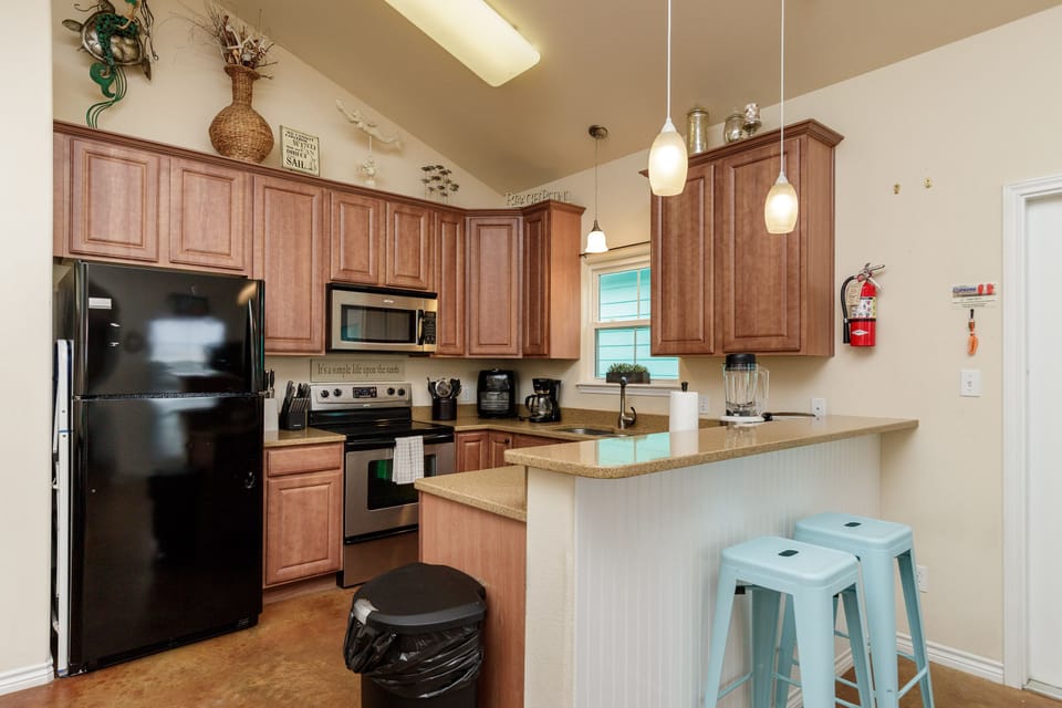 Your fully equipped kitchen features warm wood cabinets, modern appliances, and a breakfast bar where you can sip morning coffee.