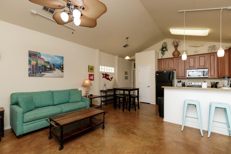 Relax in your open-concept living space where coastal-inspired decor meets modern comfort, complete with a fully equipped kitchen and cozy seating area.