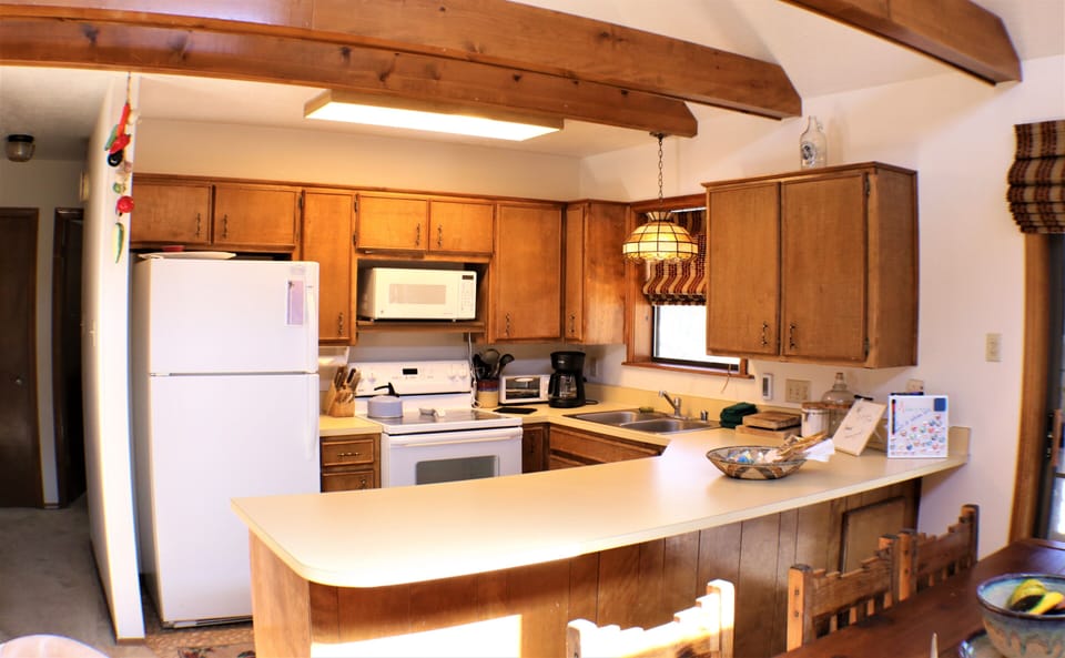 Your fully-equipped kitchen features warm wood cabinetry, bright countertops, and everything you need to prepare meals during your stay. Rustic exposed beams overhead complete the cozy retreat.