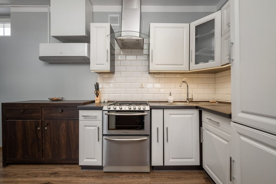 Another angle of the modern kitchen, showing white cabinetry, a countertop, and a dining area in the background.