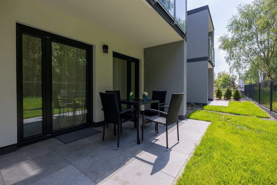 A patio area with a table and chairs outside, overlooking green grass