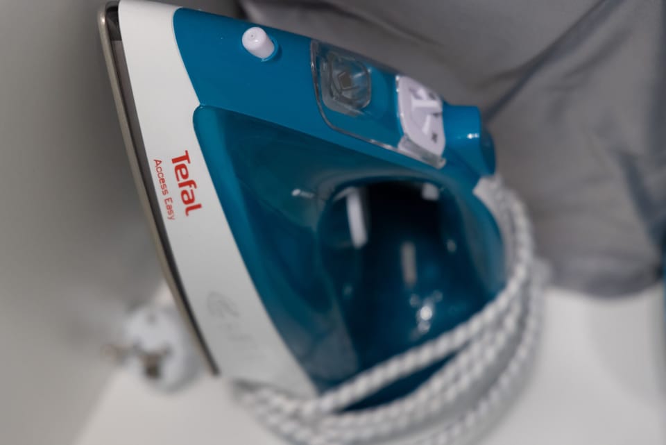 A close-up of a blue iron resting on an ironing board.