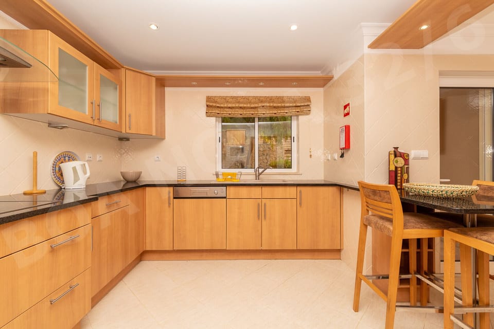 Fully equipped kitchen at Boa Nova 32/6 with warm wooden cabinets, granite worktops, breakfast bar with stools and all modern appliances for self-catering holidays in this Vilamoura apartment