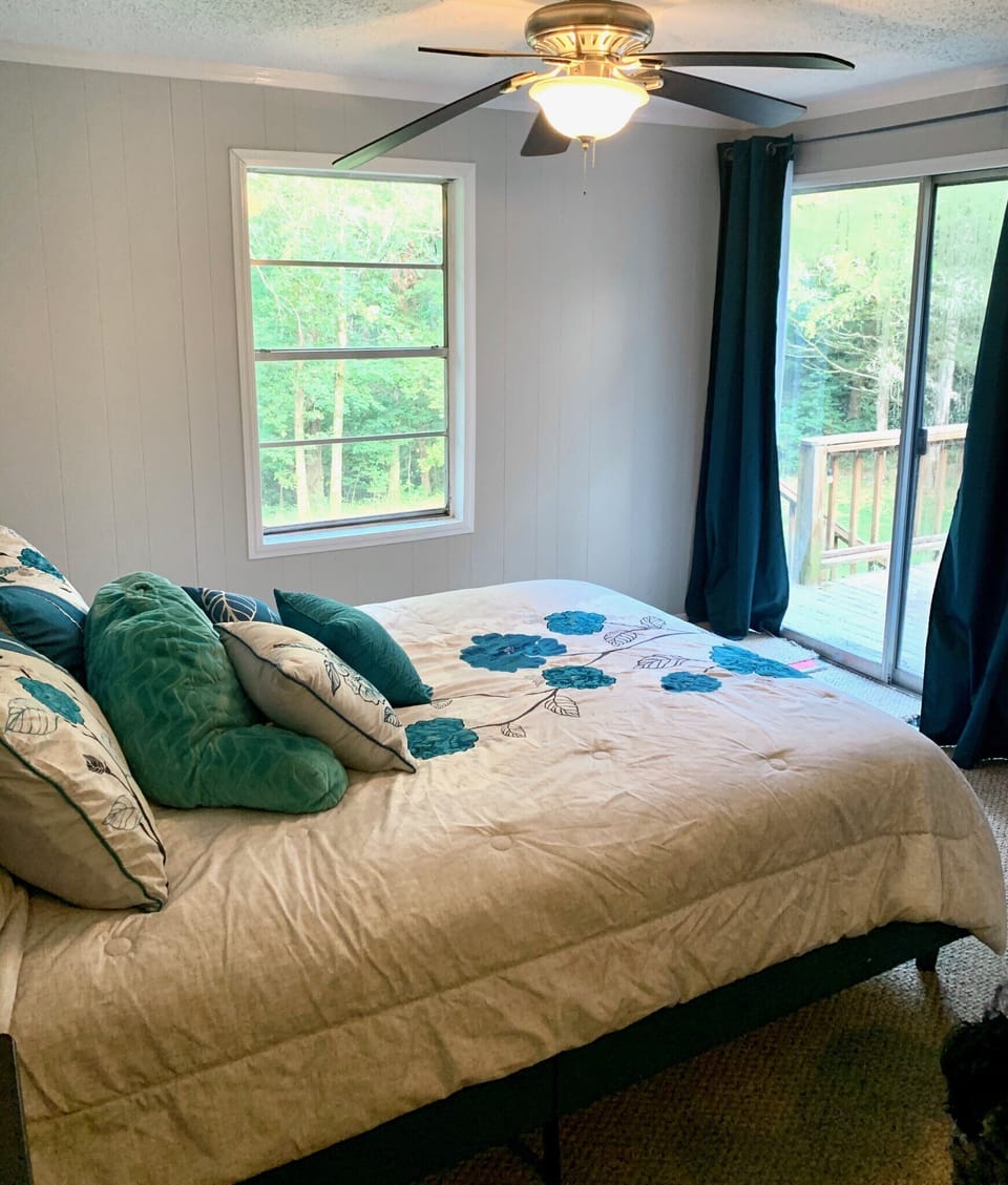 Master bedroom with view of the deck and forest. Big glass door gives open feel.
