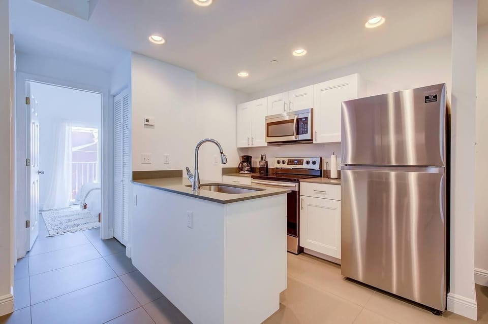 Fully equipped kitchen with electric appliances. Bedroom's door to the left. 