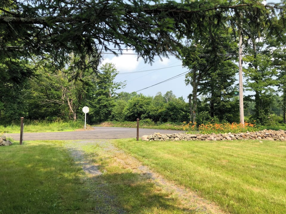 entrance and gravel driveway to the property with historic stonewalls