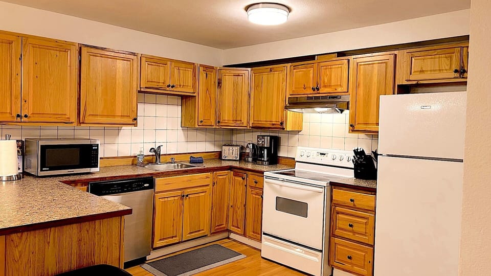 Large full kitchen with coffee pot, toaster, microwave, knife block, and plenty of dishes and cooking supplies.