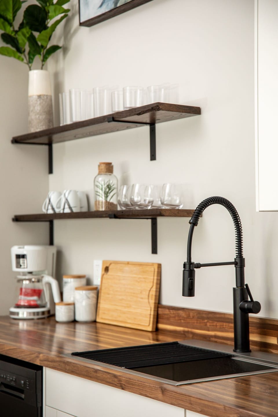 Open shelving stocked w/ glassware & essentials, paired w/ a modern pull-down faucet.