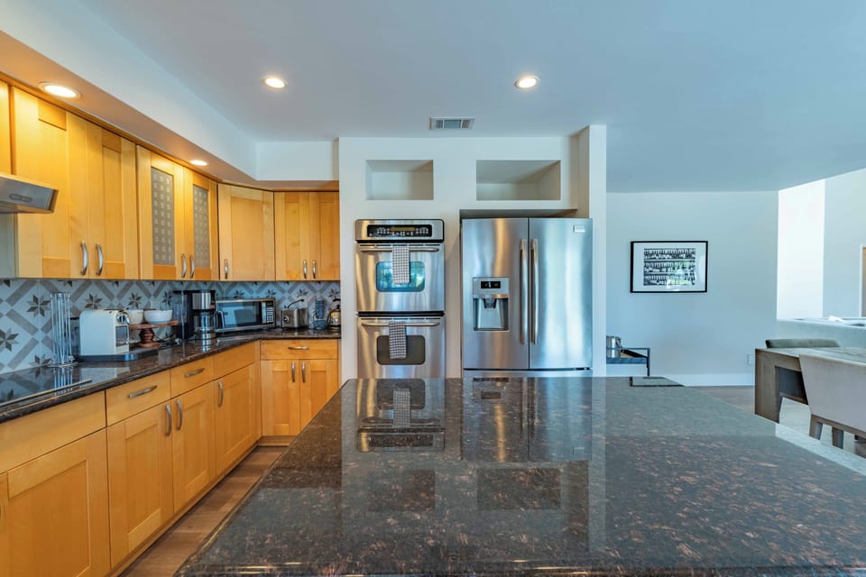 Spacious gourmet kitchen with sleek granite countertops, stainless steel appliances, and warm wood cabinetry—your perfect space for preparing meals and gathering with loved ones.