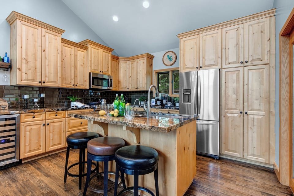 Fully Equipped Kitchen with stone countertops, wine fridge, stainless steel appliances, ice maker, and island seating for 3