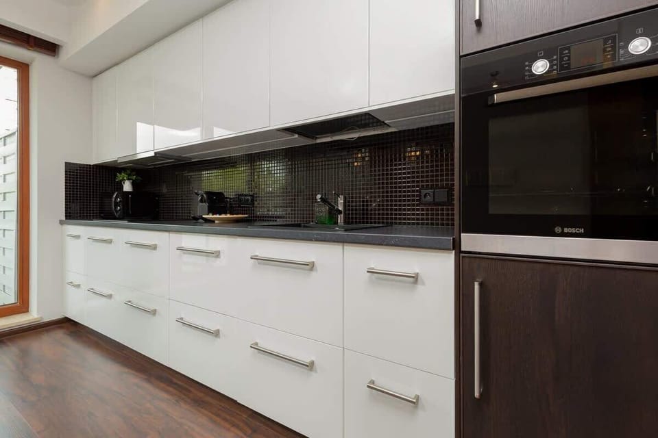Another angle of the kitchen with black upper cabinets, a long countertop, and a modern minimalist design.