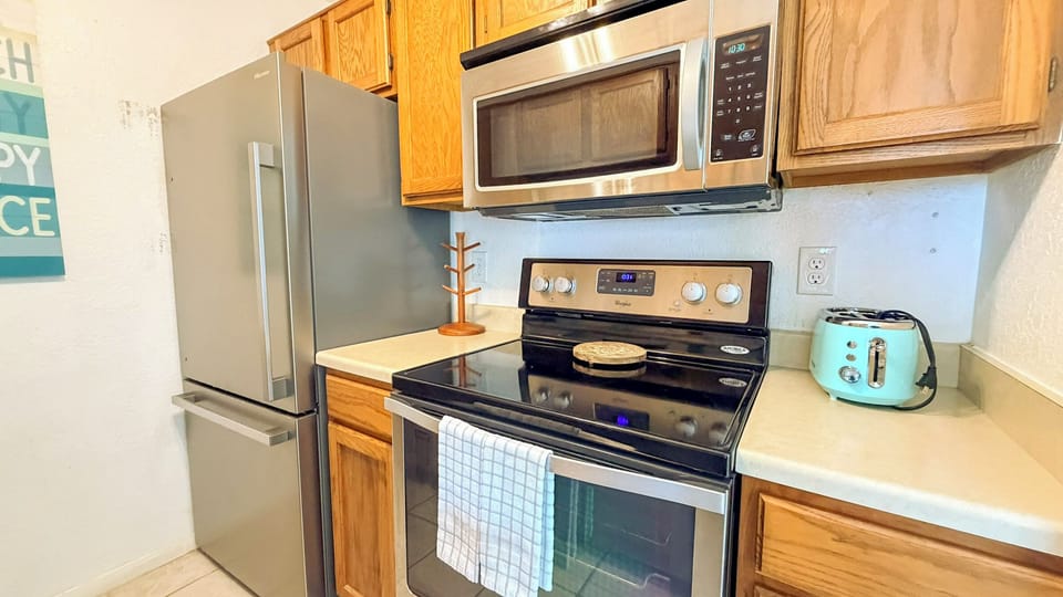 Your fully equipped kitchen awaits with stainless steel appliances, warm wood cabinets, and that charming mint toaster ready for morning treats.