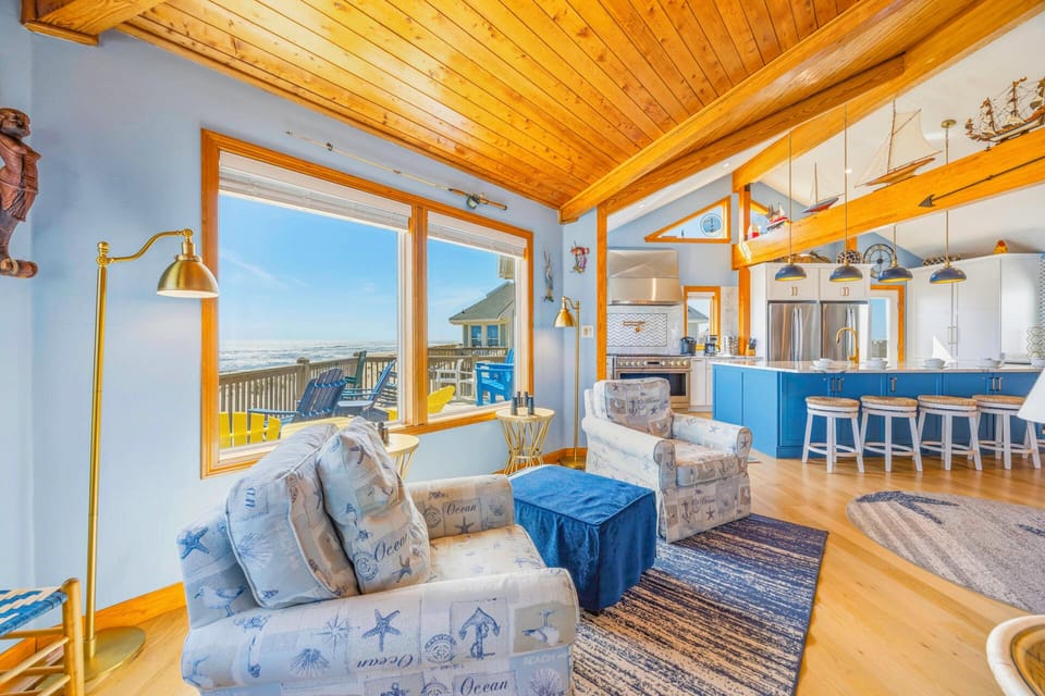 Sink into coastal-themed seating while soaking up stunning ocean views through expansive windows in this bright, open living space.