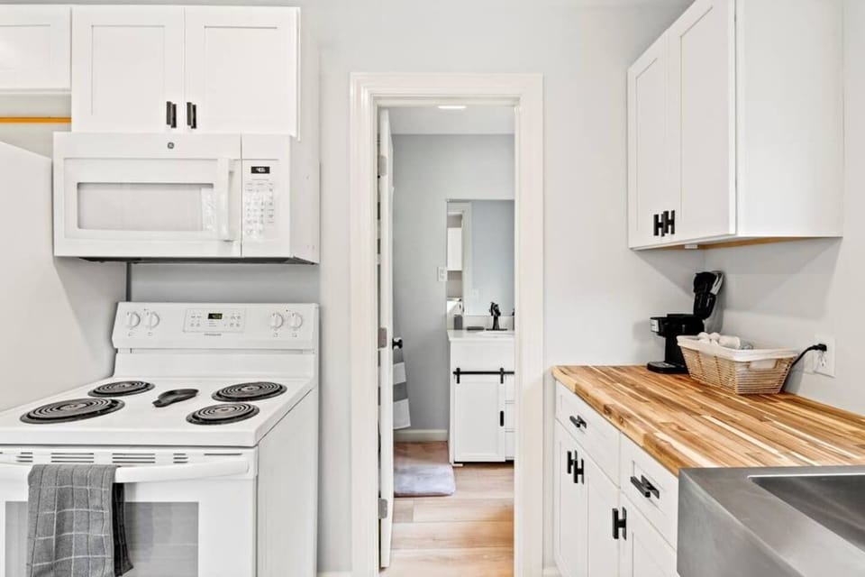 Begin your mornings in our bright, inviting kitchen with sleek white cabinetry and modern appliances, leading to a pristine bathroom—convenience meets style in this cozy corner of the home.