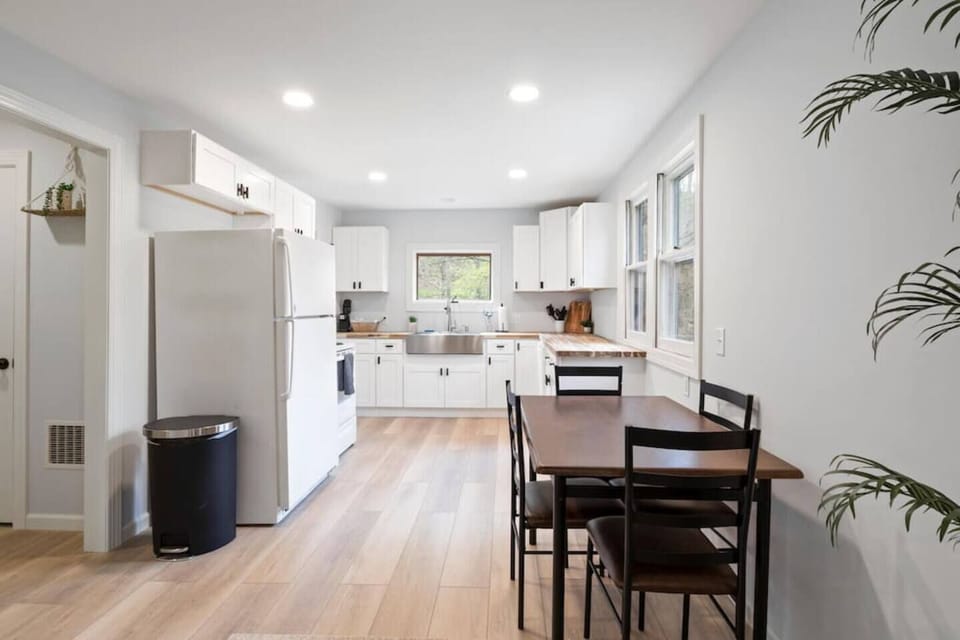 Savor your meals in our spacious kitchen, equipped with modern white appliances and a dining area that seamlessly blends style and convenience, all while offering serene views of the surrounding landscape.