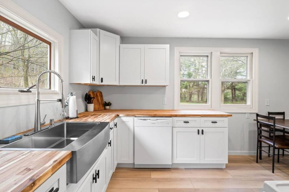 Whip up culinary delights in our bright, fully updated kitchen featuring pristine white cabinetry, stainless steel appliances, and a gorgeous wooden countertop with views of the tranquil outdoors.