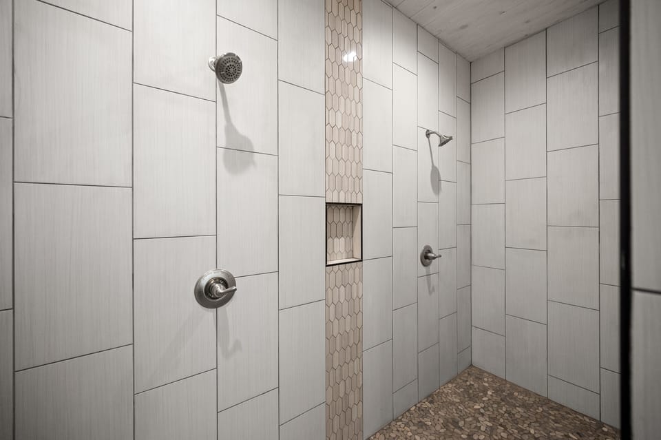 Huge walk-in shower with multiple shower heads.