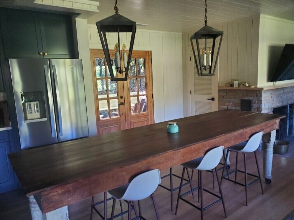 Farm table seats 8 and doors to back deck. Antique metal light fixtures. 