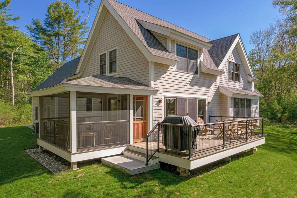 Back of the home enjoys a open deck with a gas grill as well as a enclosed porch with views of the Cape Neddick River.