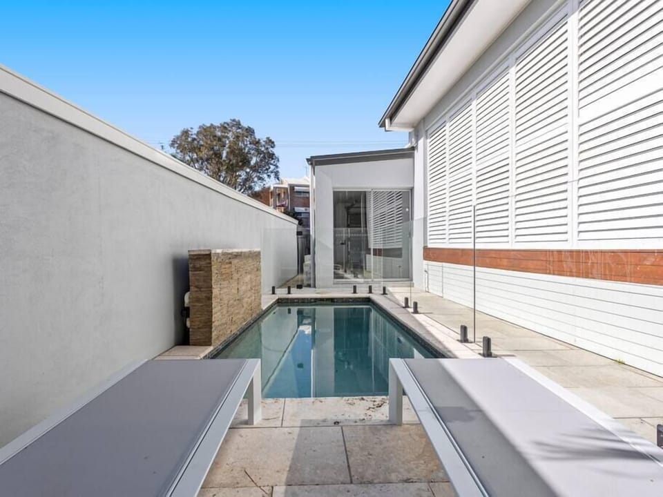 The glass-fenced heated pool has sun loungers and BBQ space at Villa Luxe Miami.