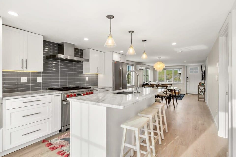 Fully equipped open kitchen and living room with large island, high-end appliances, kitchen table, washer/dryer, smart tv