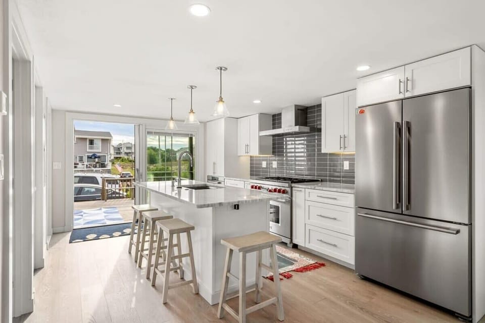 Fully equipped open kitchen and living room with large island, high-end appliances, kitchen table, washer/dryer, smart tv