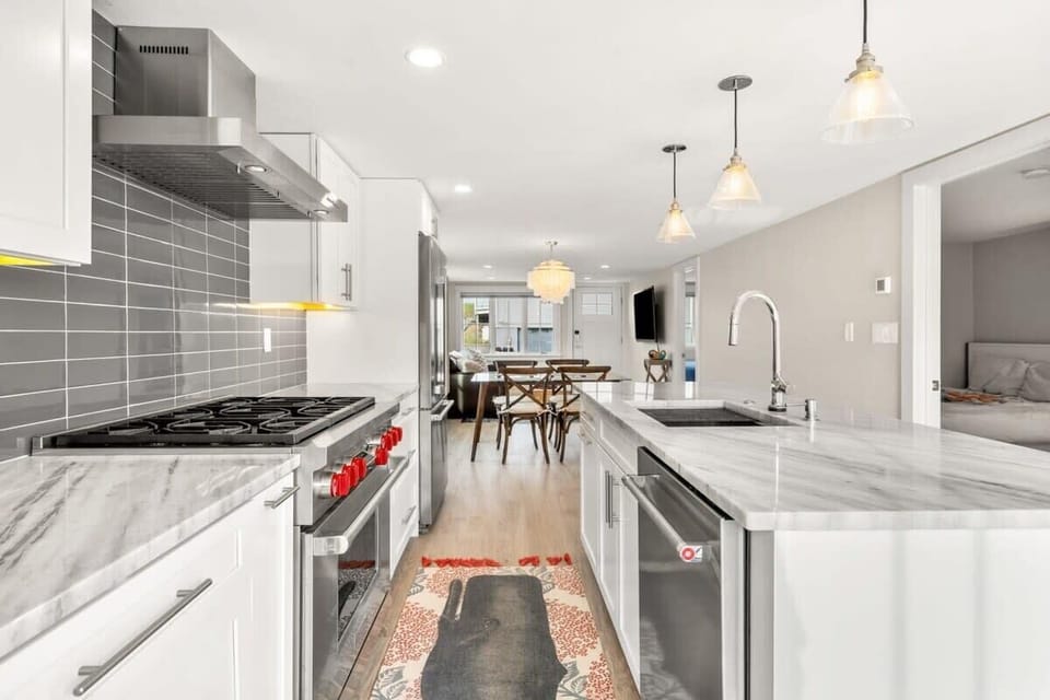 Fully equipped open kitchen and living room with large island, high-end appliances, kitchen table, washer/dryer, smart tv