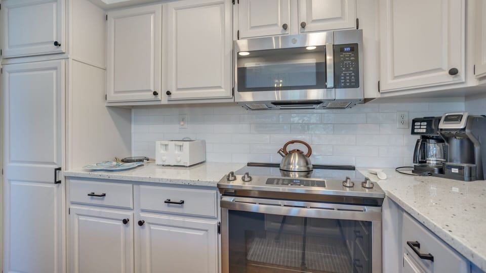 This well-appointed kitchen blends style and function with crisp white cabinetry, granite countertops, and stainless steel appliances.