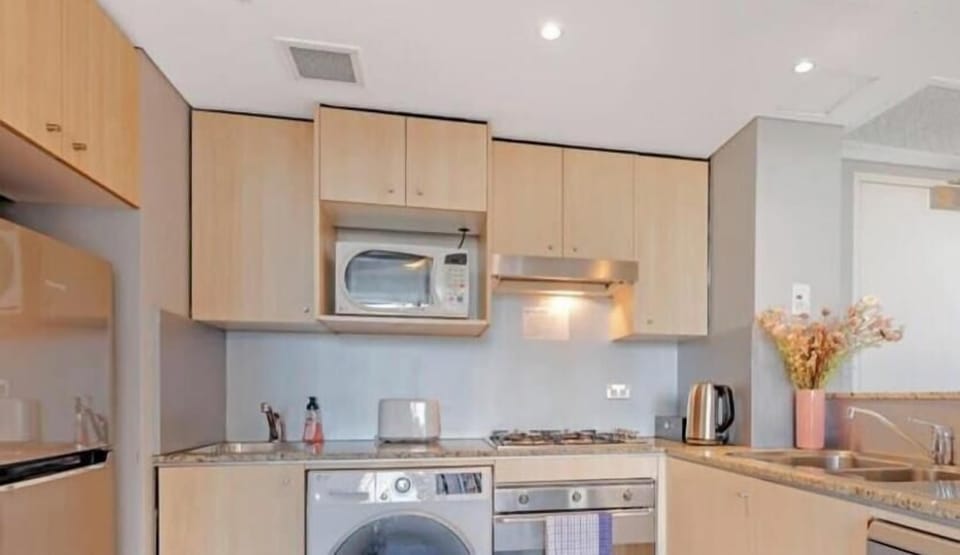 Fully equipped kitchen with cooktop, oven, microwave, washing machine, and ample cabinetry.